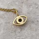 Backside of the gold eye-shaped pendant necklace on a gray surface