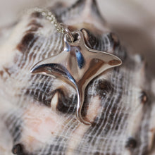 Load image into Gallery viewer, Silver manta ray pendant on a chain against a shell background
